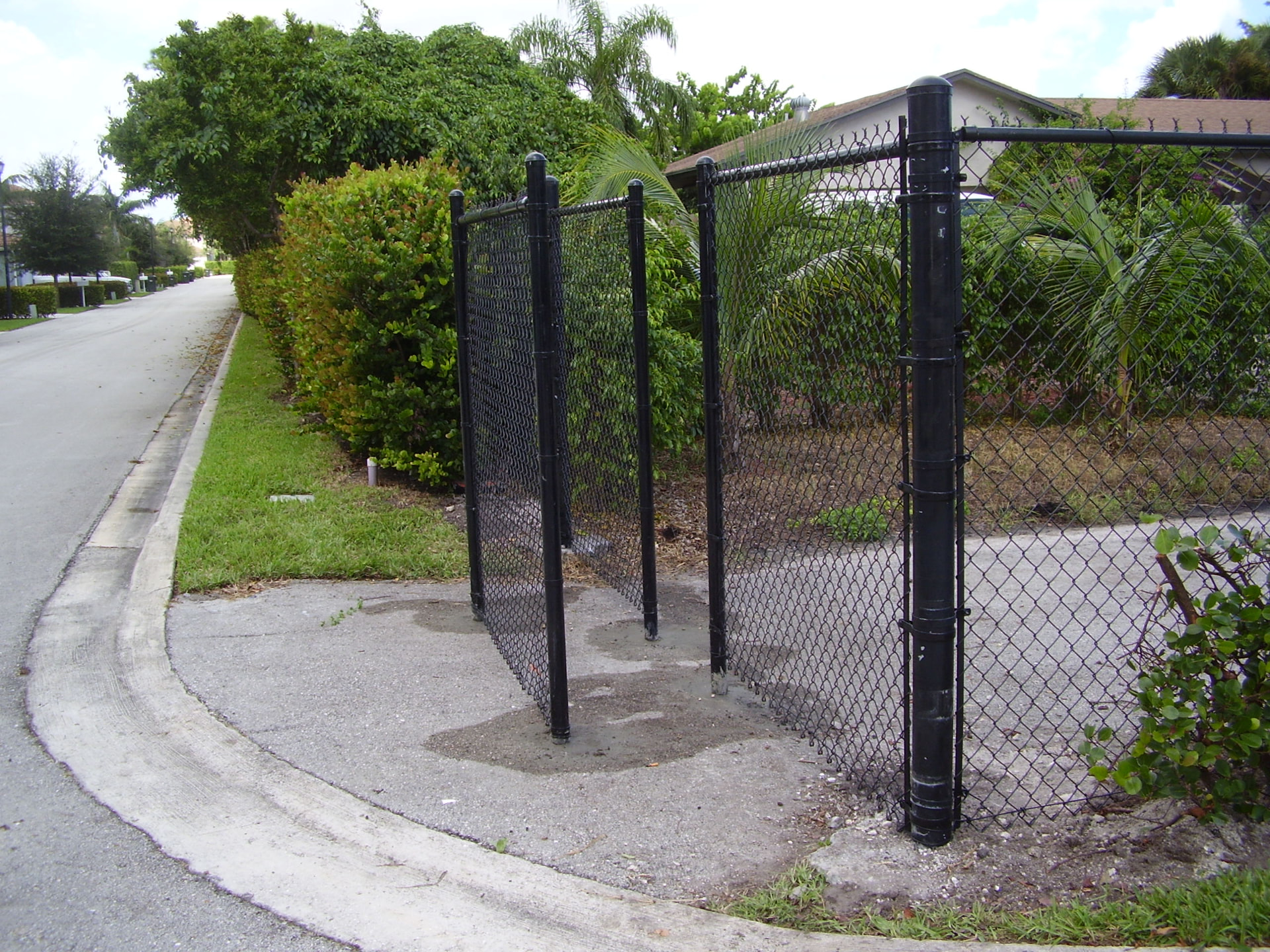 Black chain-link fence with custom double gate at a community property